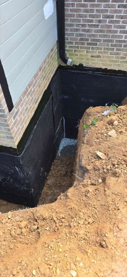 Authentic exterior foundation waterproofing process with the wall exposed and protected