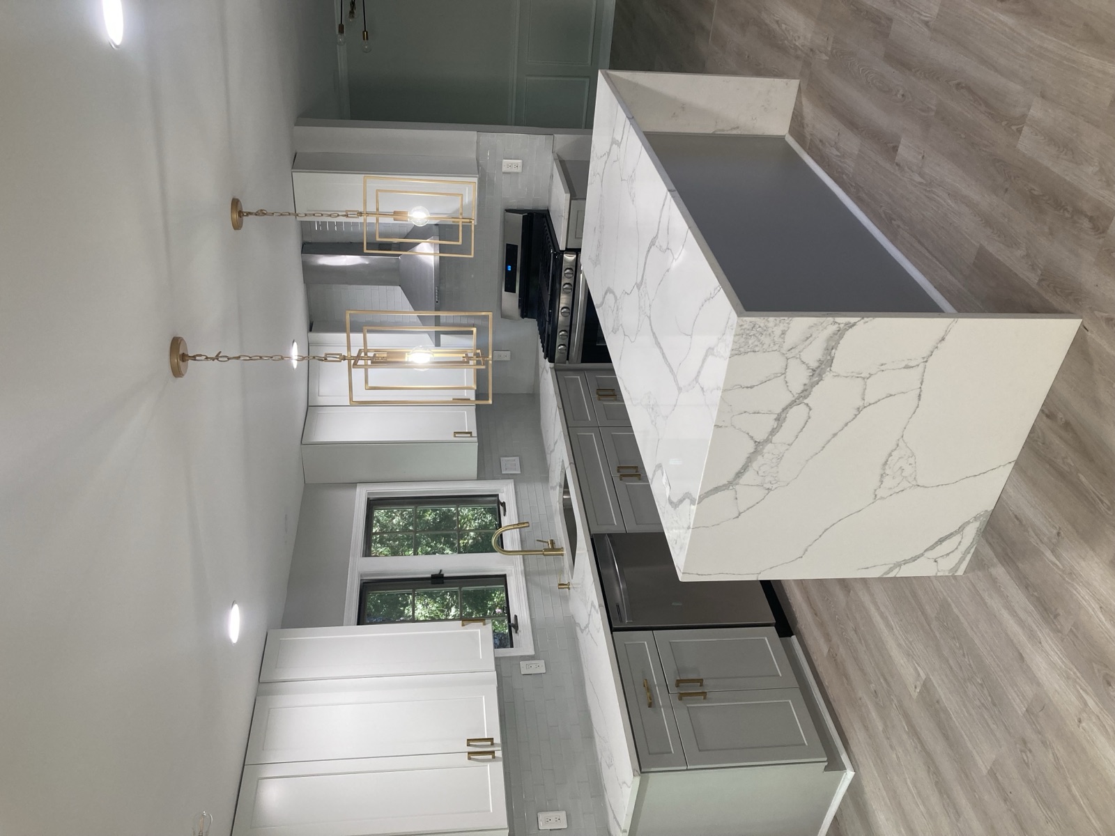Completed kitchen renovation with cabinets, countertops, tile, and lighting